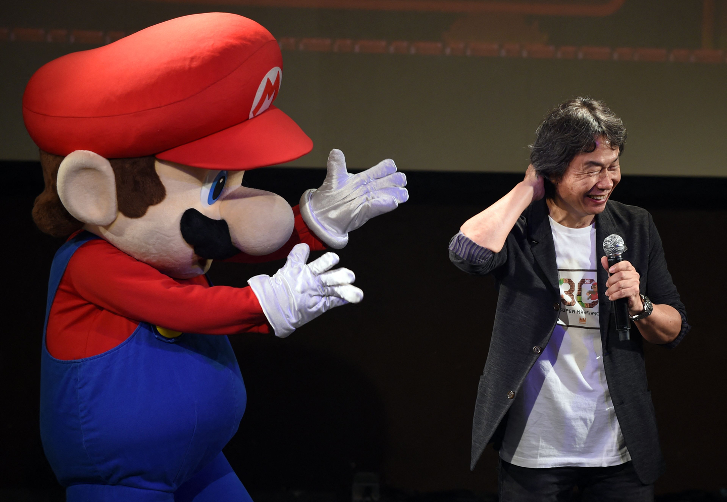 This file photo taken on September 13, 2015 shows Nintendo game creator Shigeru Miyamoto, right, reacting while standing with character ″Super Mario″ during a live performance of the most well-known Mario music to mark the game's 30th anniversary in Tokyo. September 13, 2025 marked the 40th anniversary of the release of the 'Super Mario Bros' video game by Japanese video game maker Nintendo. [AFP/YONHAP]