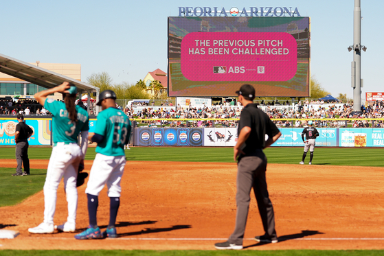An outfield screen shows a graphic indicating Seattle Mariners' Julio Rodriguez challenged a pitch call, initiating a review with the automated ball-strike challenge system, in the third inning against the Arizona Diamondbacks during a spring training baseball game on Feb. 23, in Peoria, Arizona. [AP/YONHAP]