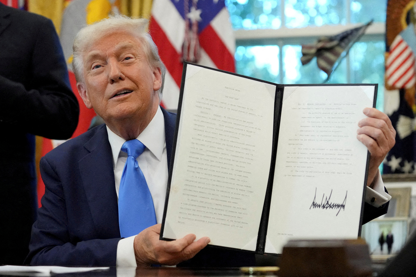 U.S. President Donald Trump displays a signed executive order on the gold card visa in the Oval Office at the White House in Washington on Sept.19. [REUTERS/YONHAP]