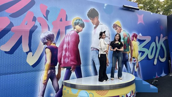 Poeple pose on a stage placed outside the Saja Boys area in the "KPop Demon Hunters" zone.[WOO JI-WON]