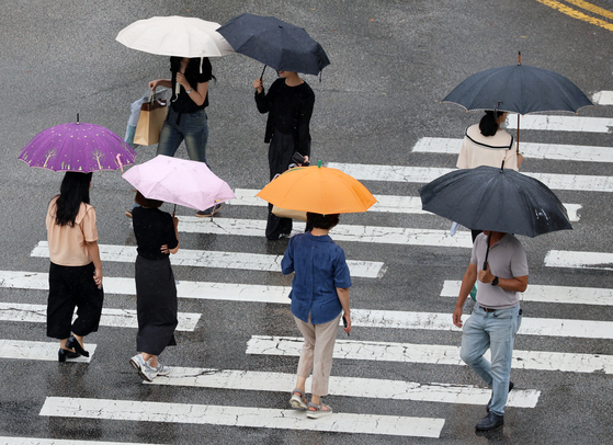 Pedestrians walk with umbrellas in the rain at an intersection in Buk District, Gwangju, on Sept. 15. [YONHAP]