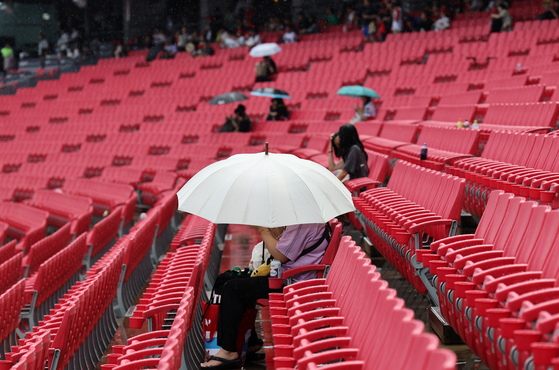 Baseball fans wait for the start of a KBO game between the KT Wiz and the Kia Tigers under umbrellas in the rain at Gwangju-Kia Champions Field on Sept. 5. [YONHAP]