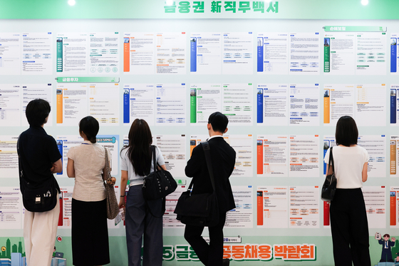 Job seekers read notices for new position openings at a job fair held at the Dongdaemun Design Plaza (DDP) in Seoul on Aug. 20. [WOO SANG-JO]