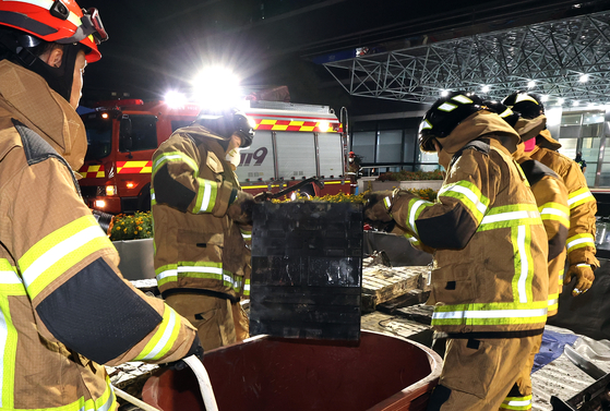 Firefighters remove burnt batteries from the National Information Resources Service in Daejeon on Sept. 27. [YONHAP]