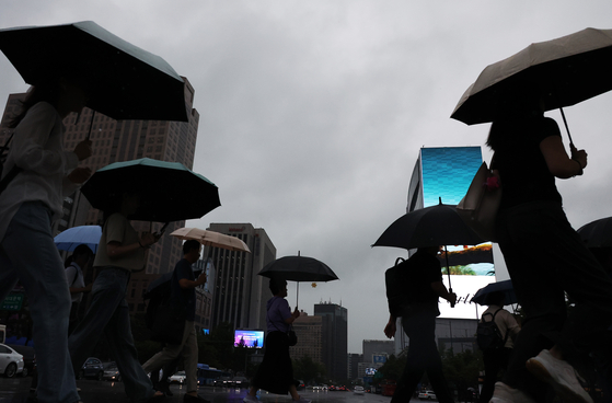 People walk with umbrellas through Gwanghwamun Square in central Seoul as it rains on the morning of Sept. 4. [YONHAP] 