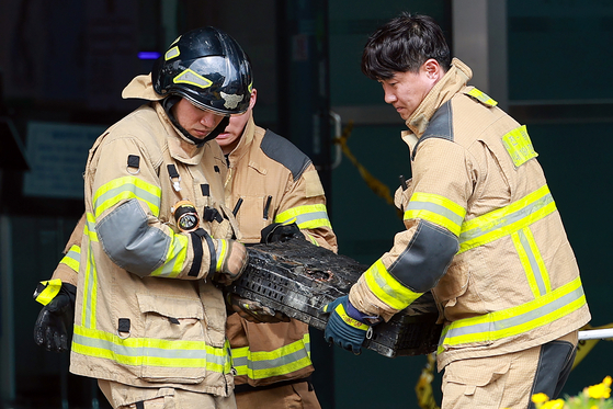 A firefighter moves a burned battery at the National Information Resources Service in Yuseong District, Daejeon, on Sept. 27. [YONHAP]