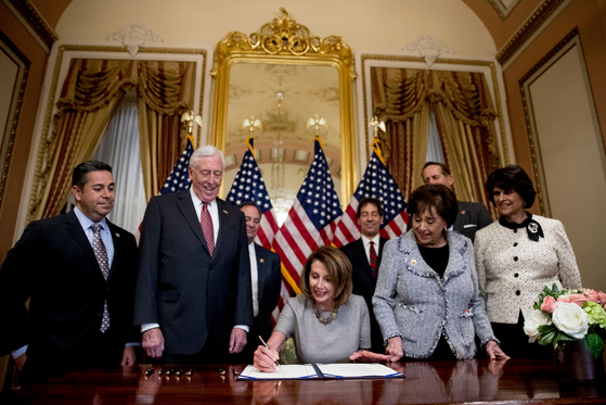 House Speaker Nancy Pelosi of Calif., center, accompanied by from left, Rep. Ben Ray Lujan, D-N.M., House Majority Leader Steny Hoyer of Md., Rep. Nita Lowey, D-N.Y, Rep. Lucille Roybal-Allard, D-Calif., and others, signs a deal to reopen the government on Capitol Hill in Washington, Jan. 25, 2019. [AP/YONHAP]