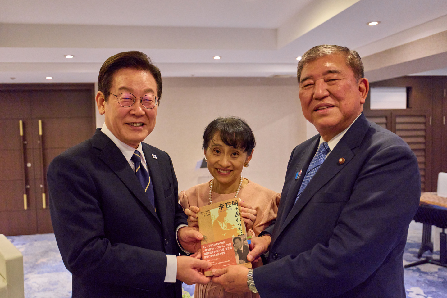 President Lee Jae Myung, left, Japanese Prime Minister Shigeru Ishiba, right, and first lady Yoshiko Ishiba hold a Japanese edition of Lee's book during a dinner event at a hotel in Busan on Sept. 30. [PRESIDENTIAL OFFICE]