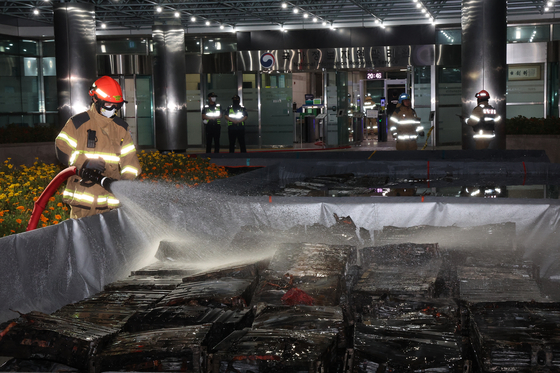 A firefighter cools down burnt batteries at the National Information Resources Service (NIRS) in Daejeon on Sept. 27. [YONHAP]