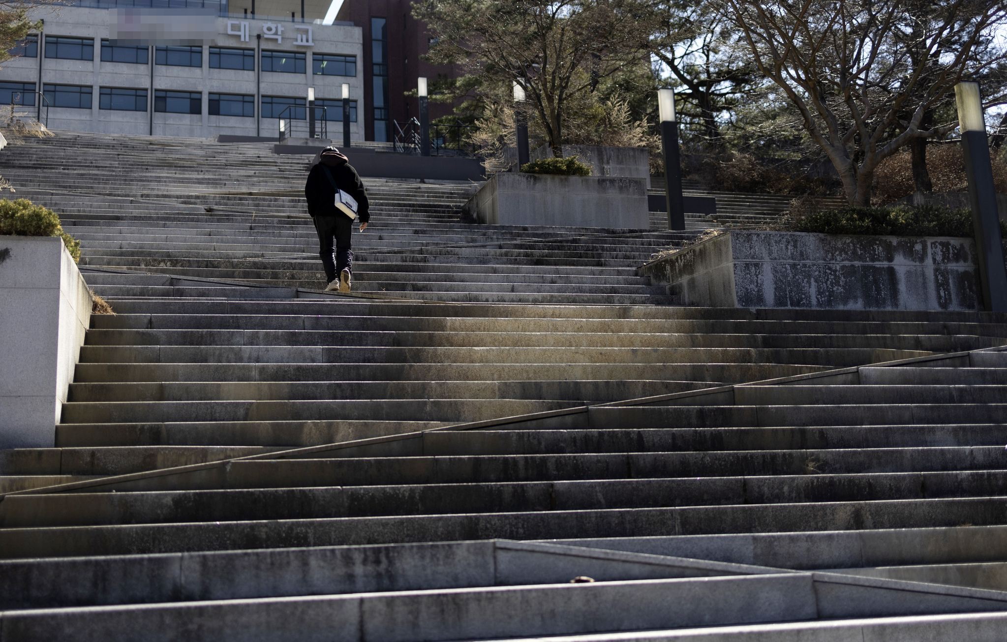 A university student walks alone up an empty staircase on March 2, 2023, the first day of the spring semester, at a provincial university in the Gyeongsang region that saw zero applicants for eight departments in its 2023 regular admissions. [YONHAP]