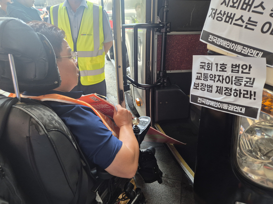 48-year-old Lee Jae-hee sits on his wheelchair in front of an express bus at the Express Bus Terminal in Seocho District, southern Seoul on Oct. 2. [JUN YUL]