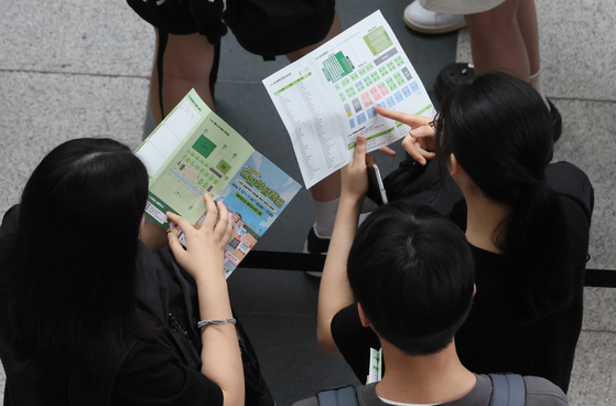 Students and their parents check out brochures at the university fair in Busan on July 14, 2024. [SONG BONG-GEUN]