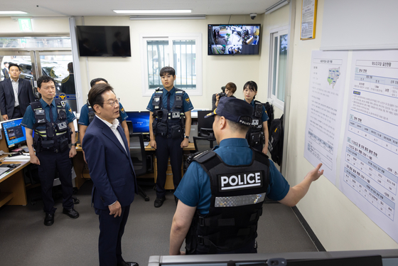 President Lee Jae Myung, left, is briefed about public security and safety efforts over the Chuseok holiday by police officers at a police station in central Seoul on Oct. 3. [PRESIDENTIAL OFFICE]