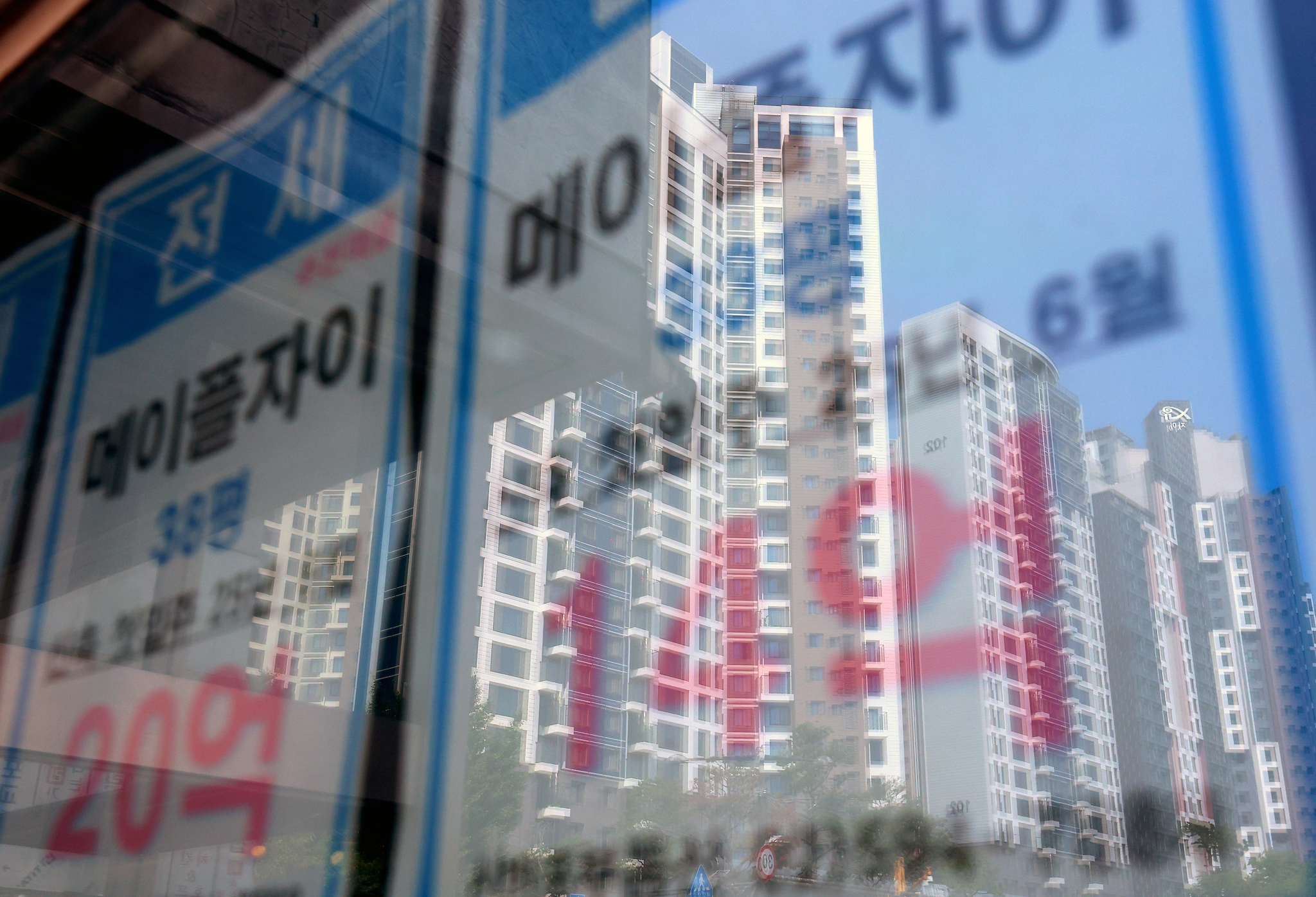 Apartments are reflected on the window of a real estate agency on June 23, 2025. [YONHAP]