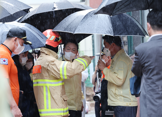 Former President Yoon Suk Yeol visits a multi-household home in Sillim-dong, Gwanak District, Seoul, on Aug. 9, 2022, where three members of a family were killed in heavy overnight rain, and listens to a briefing at the site. [JOINT PRESS CORPS]