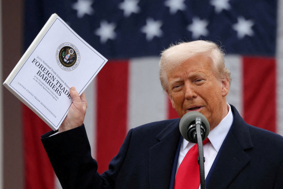 U.S. President Donald Trump holds a document titled ″Foreign Trade Barriers″ as he delivers remarks on tariffs in the Rose Garden at the White House in Washington on April 2. [REUTERS/YONHAP]