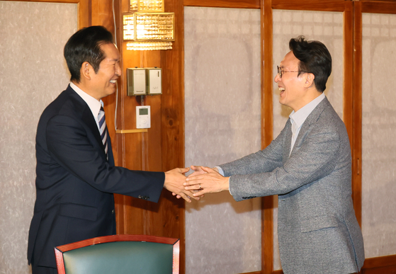 Prime Minister Kim Min-seok, right, shakes hands with Democratic Party leader Jung Chung-rae during a high-level party-government meeting at the prime minister’s official residence in central Seoul on Oct. 12. [YONHAP]