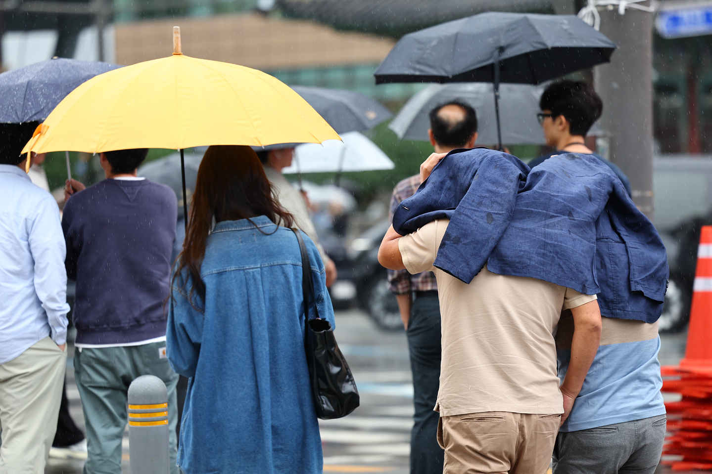 People run through Gwanghwamun Square in central Seoul, covering their heads with clothing as rain falls on Oct. 13. [YONHAP] 