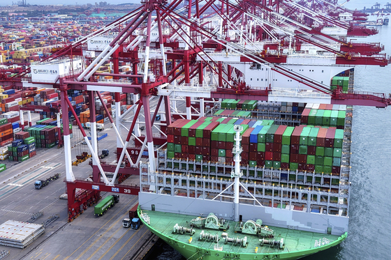 Trucks move by a vessel docked at a container terminal in Qingdao in east China's Shandong province, Aug. 11. [AP/YONHAP]
