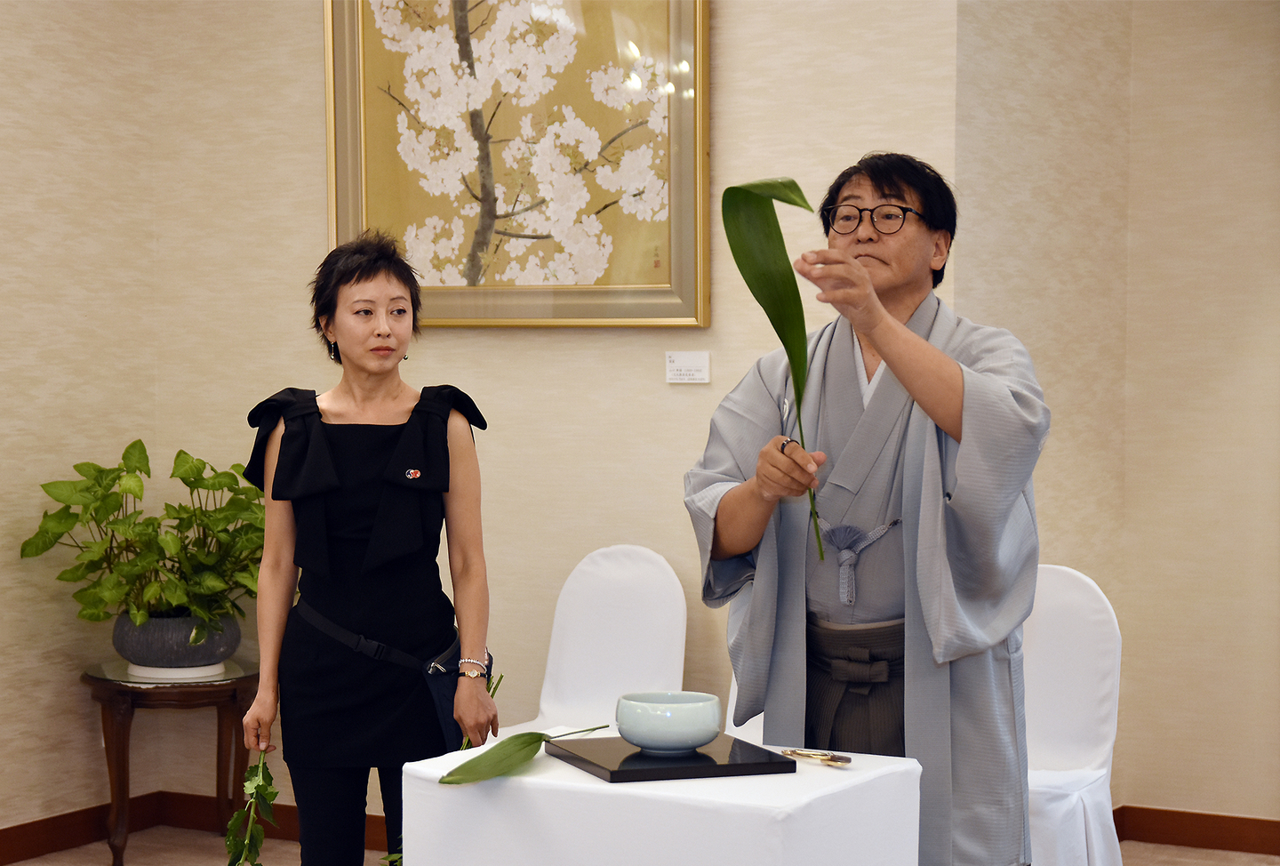 Masakazu Chiji, right, assistant professor of the Council of Ohara Professors bends a leaf while demonstrating a moribana-style arrangement during “Autumn Ikebana: Flowers of Friendship for a Shared Future” at the Japanese ambassador’s residence in Seoul on Oct. 10 [EMBASSY OF JAPAN]