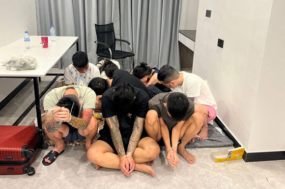 This pool photo taken on July 14 and released on July 16 by Agence Kampuchea Presse shows suspects with their hands ziptied after being detained during a raid on a scam centre in Phnom Penh, Cambodia. [AFP/YONHAP]