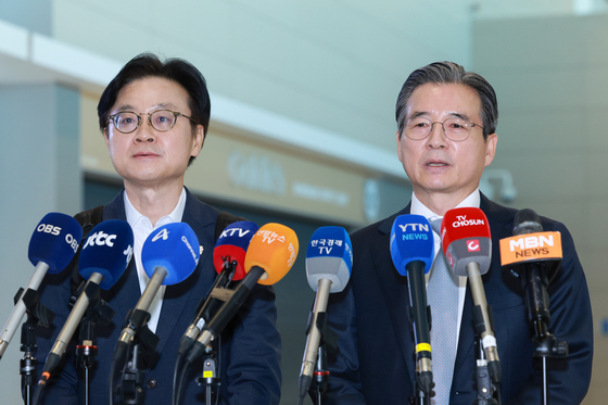 Kim Yong-beom, right, the presidential chief of staff for policy, and Industry Minister Kim Jung-kwan, left, field questions from reporters at Incheon International Airport, west of Seoul, on Oct. 16, before their departure for Washington for trade talks with the United States. [YONHAP]