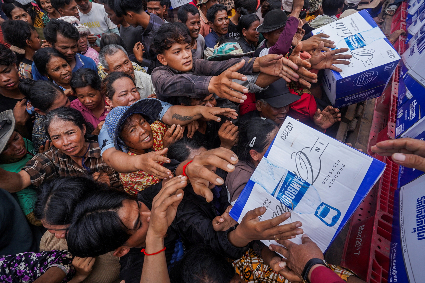 People gather to receive water supplies donated at Batthkao Primary School camp, amid ongoing clashes on the Thai-Cambodian border that extended to the third day, with new flashpoints emerging as both sides seek diplomatic support and urge for negotiations, in Oddar Meanchey province, Cambodia on July 26. [REUTERS/YONHAP]