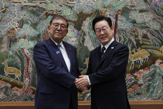 South Korean President Lee Jae Myung, right, shakes hands with Japanese Prime Minister Shigeru Ishiba at the APEC House in Busan on Sept. 30. [JOINT PRESS CORPS]