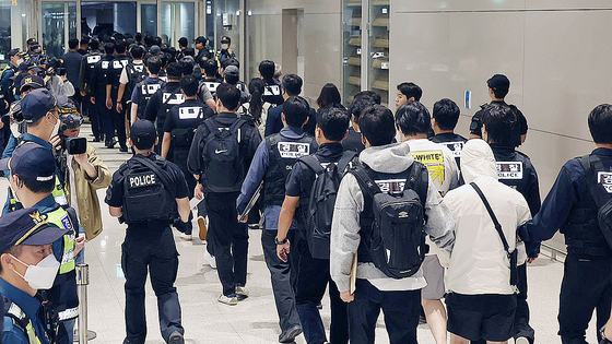 Koreans who were arrested in a Cambodian criminal compound sweep and repatriated walk through Terminal 2 of Incheon International Airport on the morning of Oct. 18. [NEWS1]