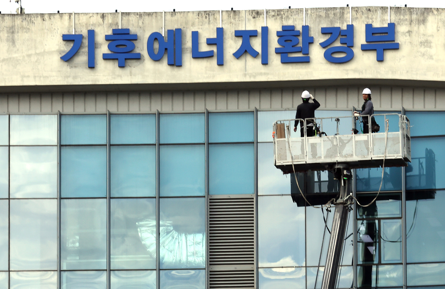 The government’s reorganization plan to transfer core energy policy functions to the newly established Ministry of Climate, Energy and Environment was approved at a Cabinet meeting on Sept. 30. Workers install the ministry’s nameplate on the exterior of the Government Complex Sejong building the same day. [YONHAP]