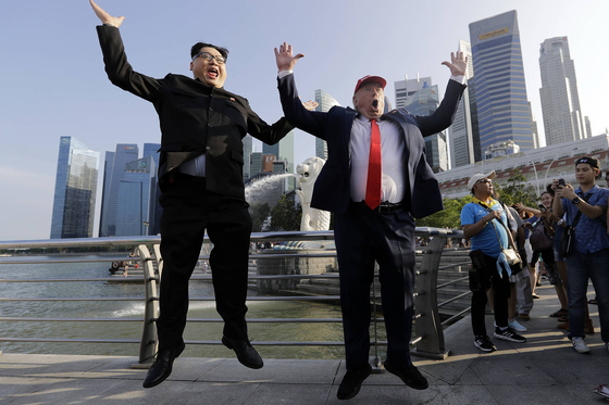Howard X, left, who impersonates North Korean leader Kim Jong-un, and Dennis Alan, who impersonates U.S. President Donald Trump, jump for a photo at Merlion Park in Singapore on June 8, 2018. [AP/YONHAP]