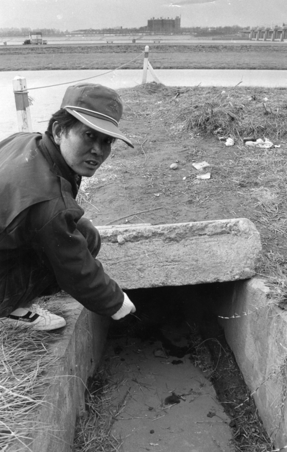 A man points to the drainage culvert on the Han River in Jamsil District, southern Seoul, where the corpse of nine-year-old Lee Hyung-ho was found on March 13, 1991. [JOONGANG ILBO]