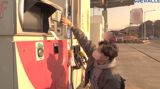 YouTuber Park We, who uses a wheelchair, attempts to use a self-service gas station in 2020. Seated in his wheelchair, he struggles to reach the payment terminal due to its height. [SCREEN CAPTURE]