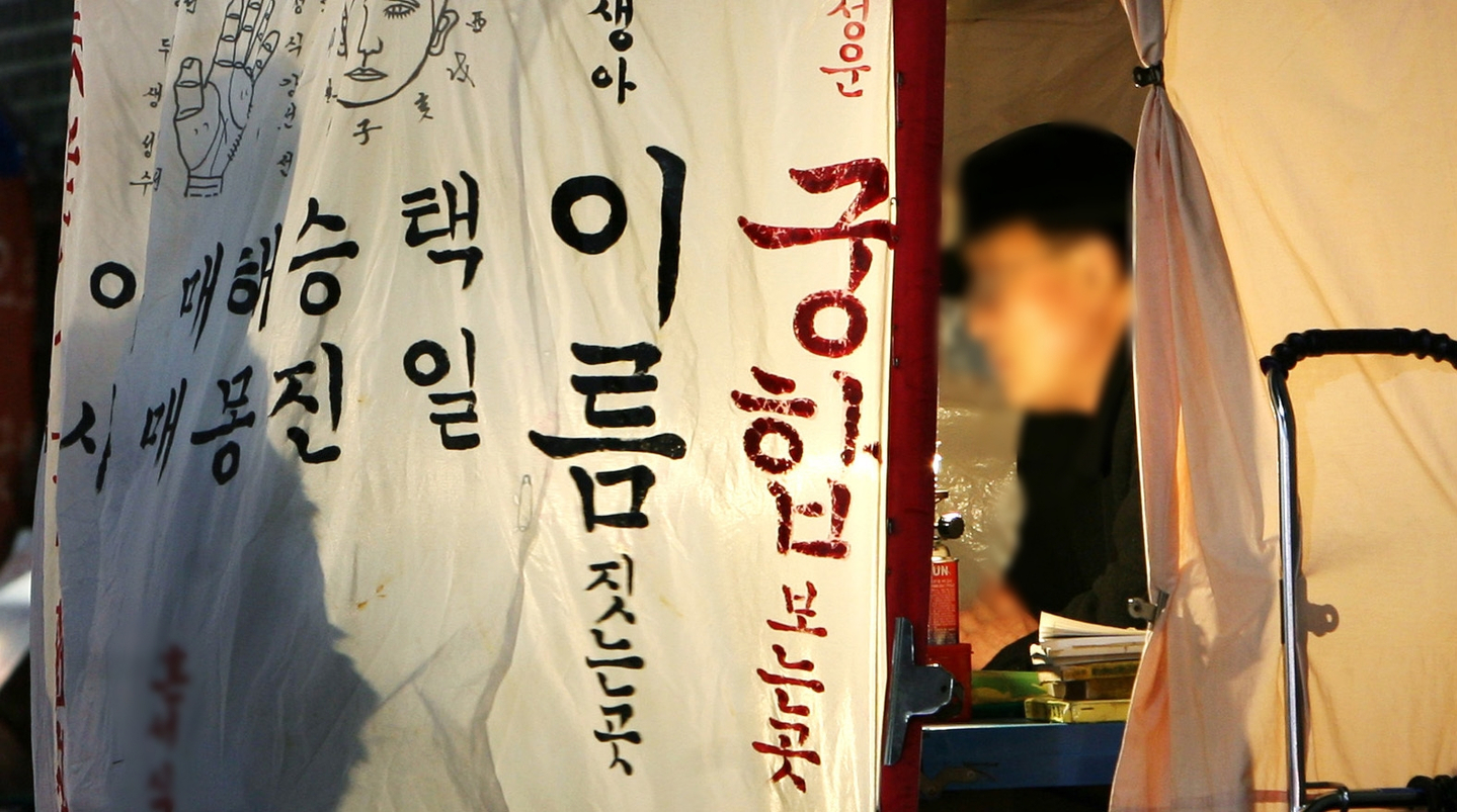 A fortune-teller welcomes visitors at a saju (fortune-reading) booth in Jongno, central Seoul, on Jan. 10, 2008. [JOONGANG ILBO]