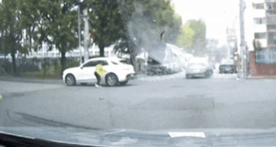 A screenshot from a video of a woman performing a traditional blessing ritual for her new car in the middle of a street [SCREEN CAPTURE]