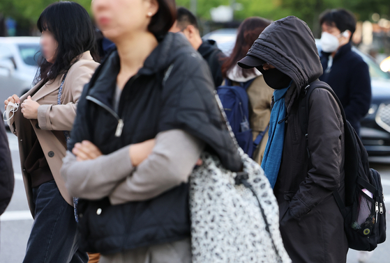Commuters hurry through Gwanghwamun Intersection in central Seoul, bracing against the early winter cold on the morning of Oct. 21. [NEWS1]