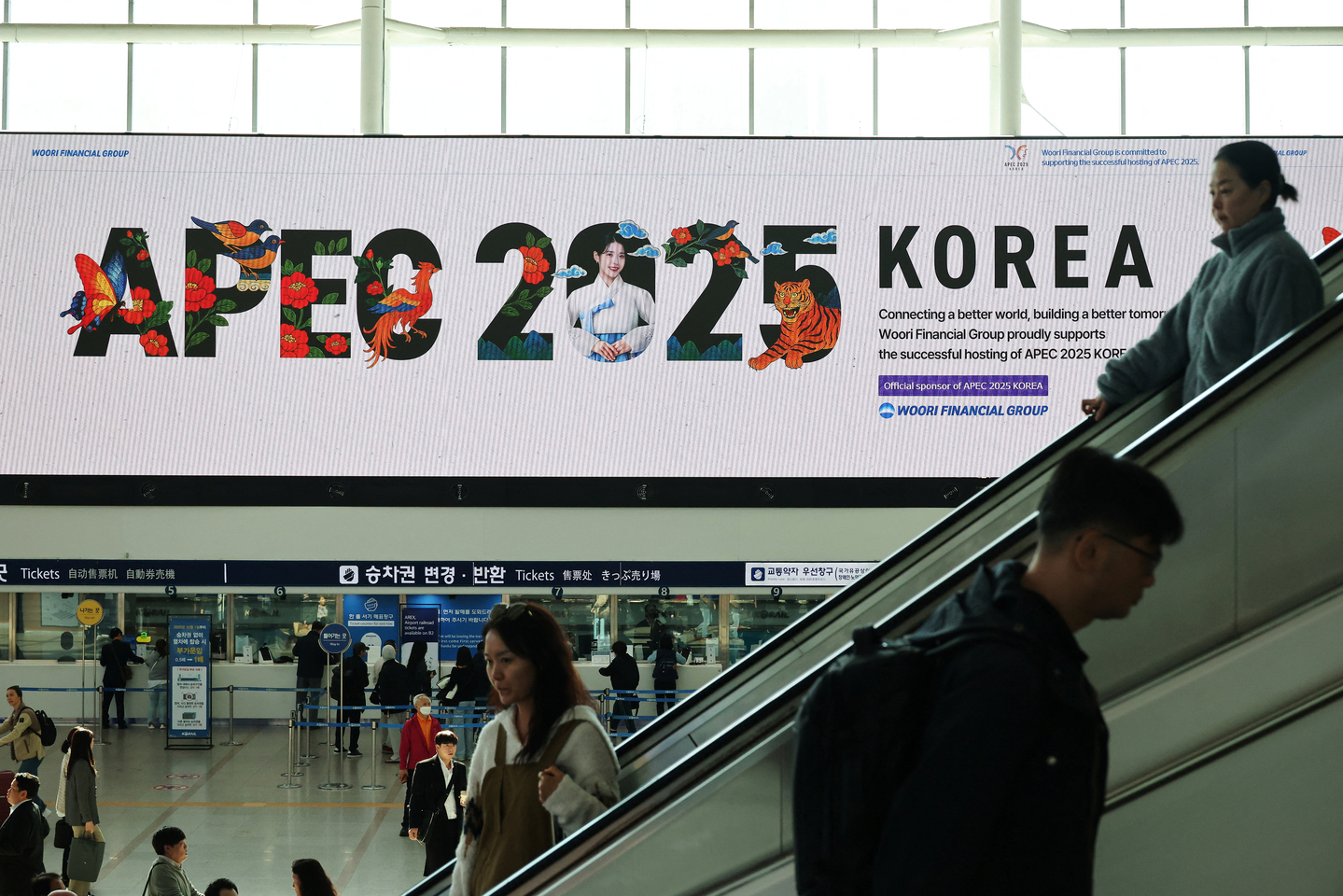 Passengers ride on escalators as a large electric board shows an advertisement promoting the 2025 APEC Economic Leaders' Meeting in Gyeongju at Seoul Station on Oct. 22. [REUTERS/YONHAP]