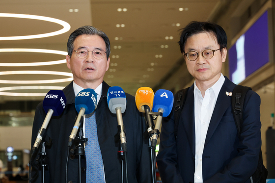Presidential Director of National Policy Kim Yong-beom, left, and Industry Minister Kim Jung-kwan, right, speak to reporters upon returning from the United States at Incheon International Airport on Oct. 24. [YONHAP]