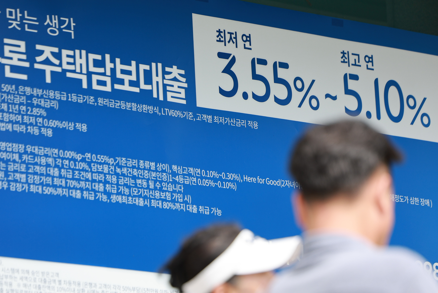 Pedestrians walk by a banner advertising home mortgage loan products at a bank in Seoul on Sept. 7. [YONHAP] 