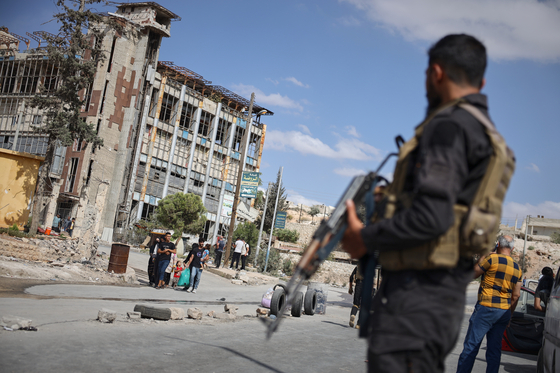 Syrian security forces stand guard as residents leave the Sheikh Maqsoud and Achrafieh neighborhoods of Aleppo, Syria on Oct. 7, following overnight clashes between Syrian government troops and the Kurdish-led Syrian Democratic Forces. [AP/YONHAP]