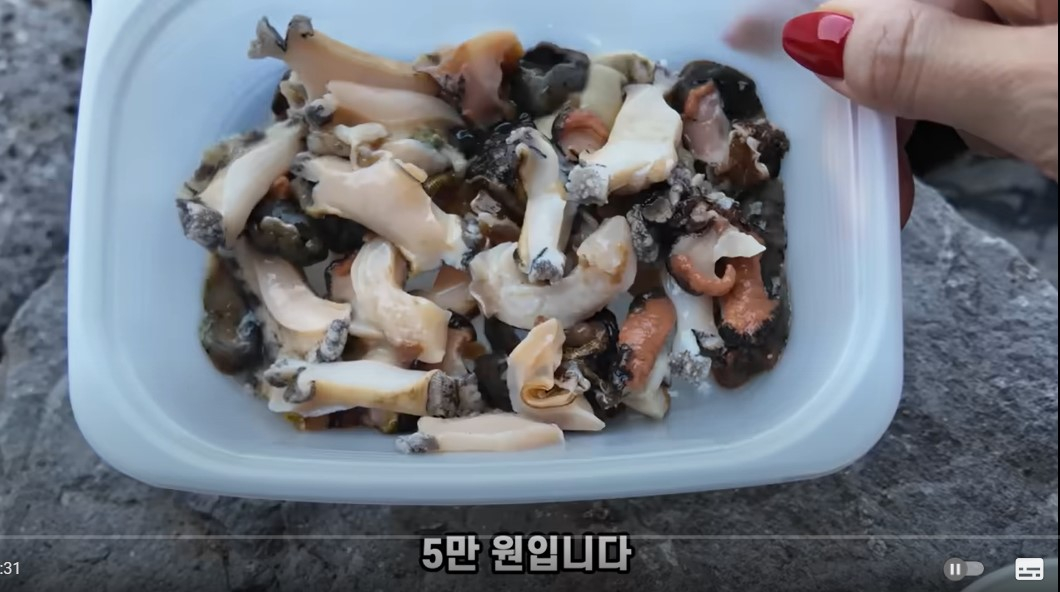 A visitor to shop in Jeju holds up 50,000 won ($35) worth of seafood, claiming it was overpriced, in a video uploaded in 2024 by content creator hakuzzang. [SCREEN CAPTURE]