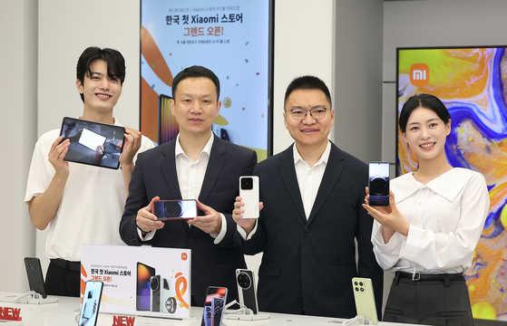 Xiaomi International Business Department East Asia Region General Manager Andrew Li, second from right, and Xiaomi Korea General Manager Jony Wu, second from left, pose together with the models during the opening of the brand's first Korean official retail store at IFC Mall in Yeouido, Seoul, on June 25. [NEWS1] 
