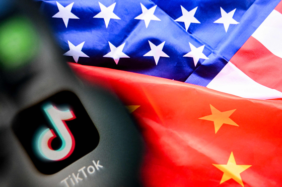 A photo taken on April 10 shows the Chinese social networking service TikTok's logo on a smartphone screen, left, and the United States and China flags combo illustration. [AFP/YONHAP]