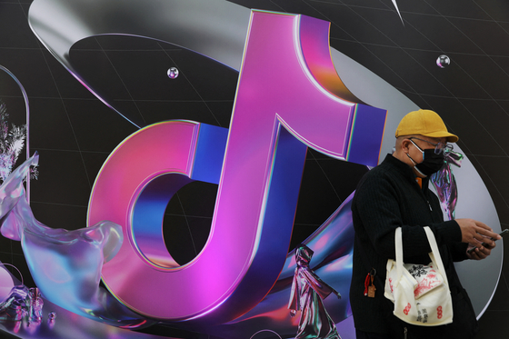 A man stands near a giant sign of Chinese company ByteDance's app TikTok, known locally as Douyin, during China Fashion Week, in Beijing, China on March 31. [REUTERS/YONHAP]