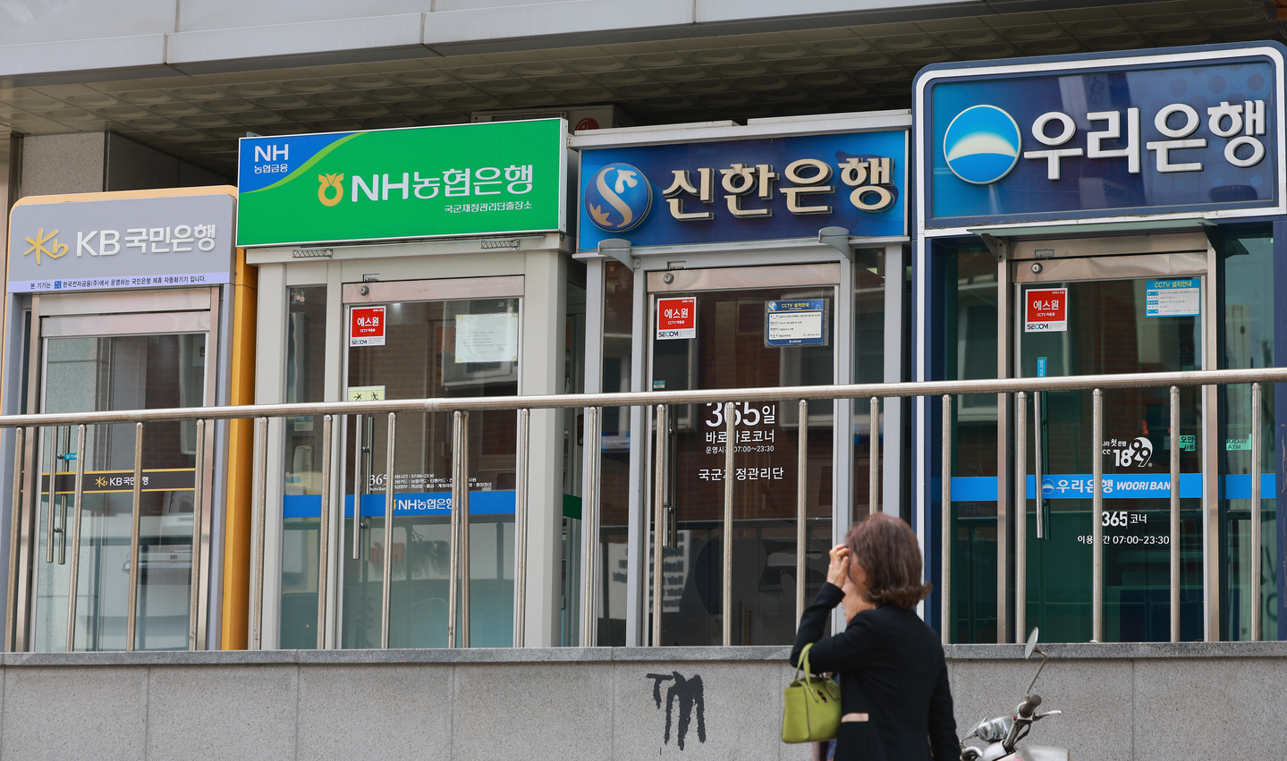 A pedestrian walks by ATMs in Seoul on April 27. [YONHAP] 