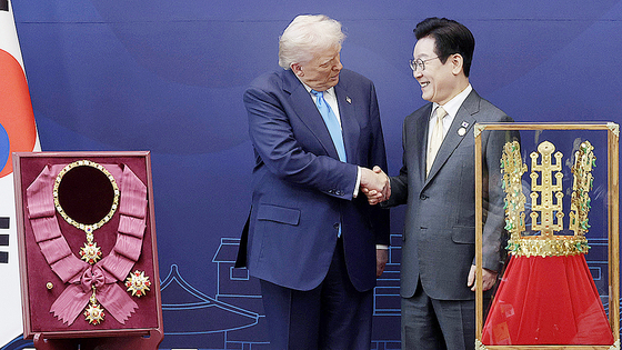 U.S. President Donald Trump moves to shake hands with Korean President Lee Jae Myung as he receives a gift of a gold crown and an award of the Grand Order of Mugunghwa, not seen, during a high honor ceremony at the Gyeongju National Museum in Gyeongju, North Gyeongsang, Oct. 29. [AP/YONHAP] 