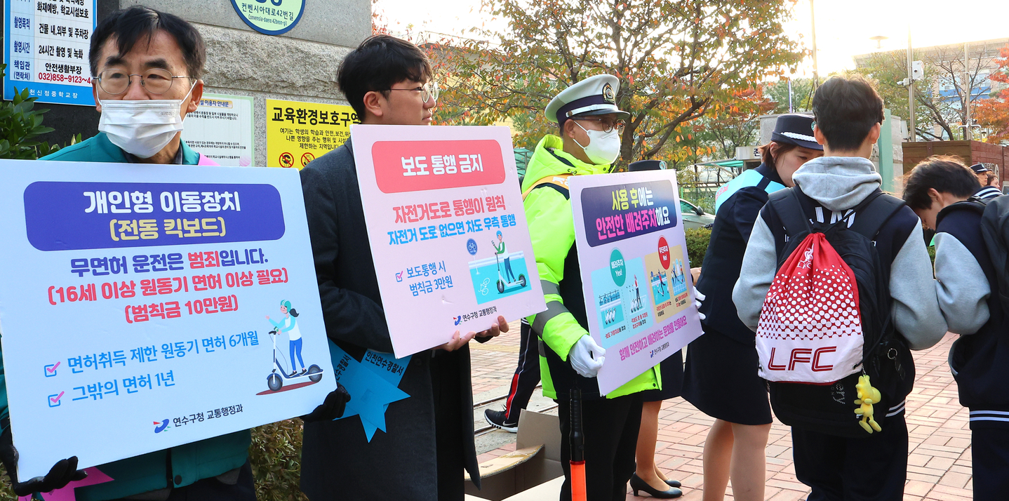 Officials and volunteers from the Yeonsu District Office and Yeonsu Police Station conduct an “e-scooter safety campaign” for students in front of Incheon Sinjeong Middle School and Incheon Yeonsong High School in Incheon on Oct. 29. [YONHAP]