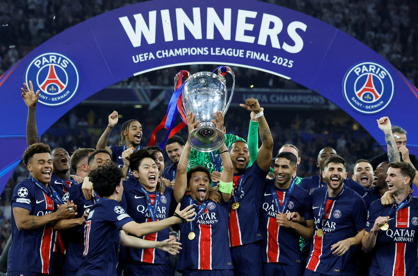 Paris Saint-Germain captain Marquinhos lifts the trophy as he celebrates with teammates after winning the Champions League on May 31. [REUTERS/YONHAP]