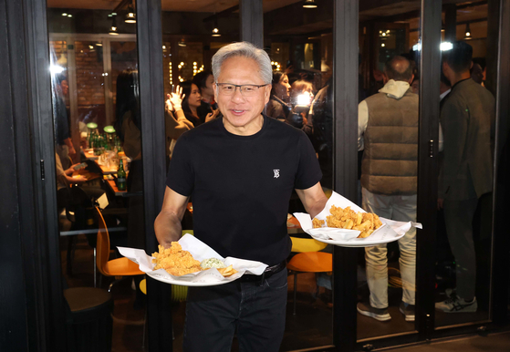 Nvidia CEO Jensen Huang hands out fried chicken to citizens during a “chimaek” (chicken and beer) gathering with Samsung Electronics Executive Chairman Lee Jae-yong and Hyundai Motor Group Executive Chair Euisun Chung at a chicken restaurant in Samseong-dong, Gangnam District, Seoul, on Oct. 30. [JOINT PRESS CORPS]