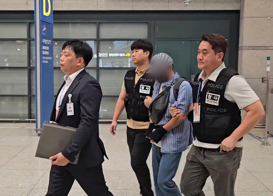 The photo released on Nov. 3 shows one of the suspects being extradited through Incheon International Airport after police arrested 114 members of a Cambodia-based crime ring that posed as military units, political parties and the presidential security service to carry out fraud schemes. [YONHAP]